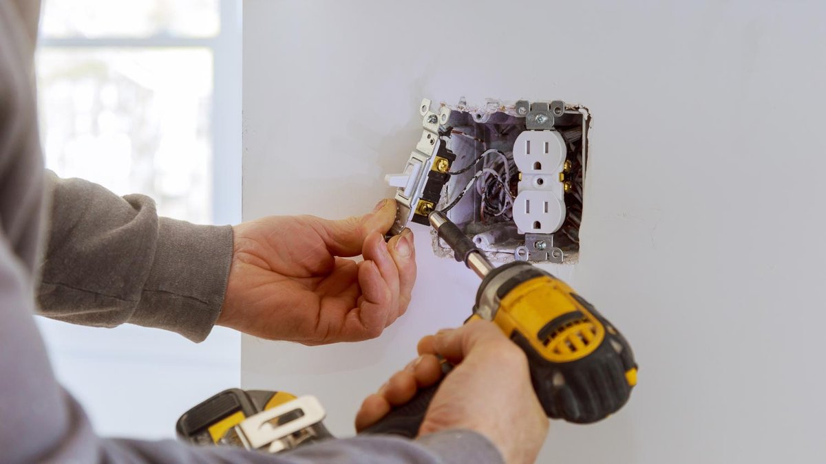 Electrician installing a new outlet and switch in a residential wall